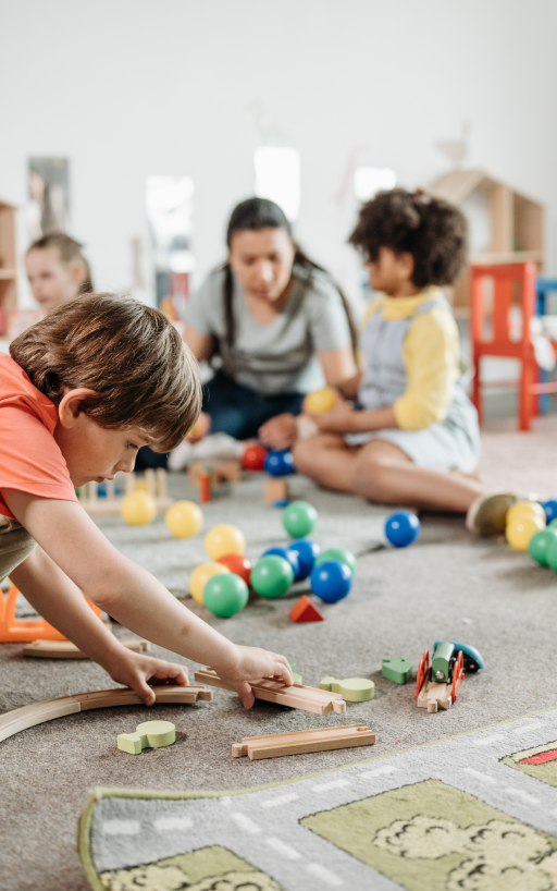 Kinder spielen mit Spielzeug in einem Spielzimmer, während sie von ihren Eltern beobachtet werden.